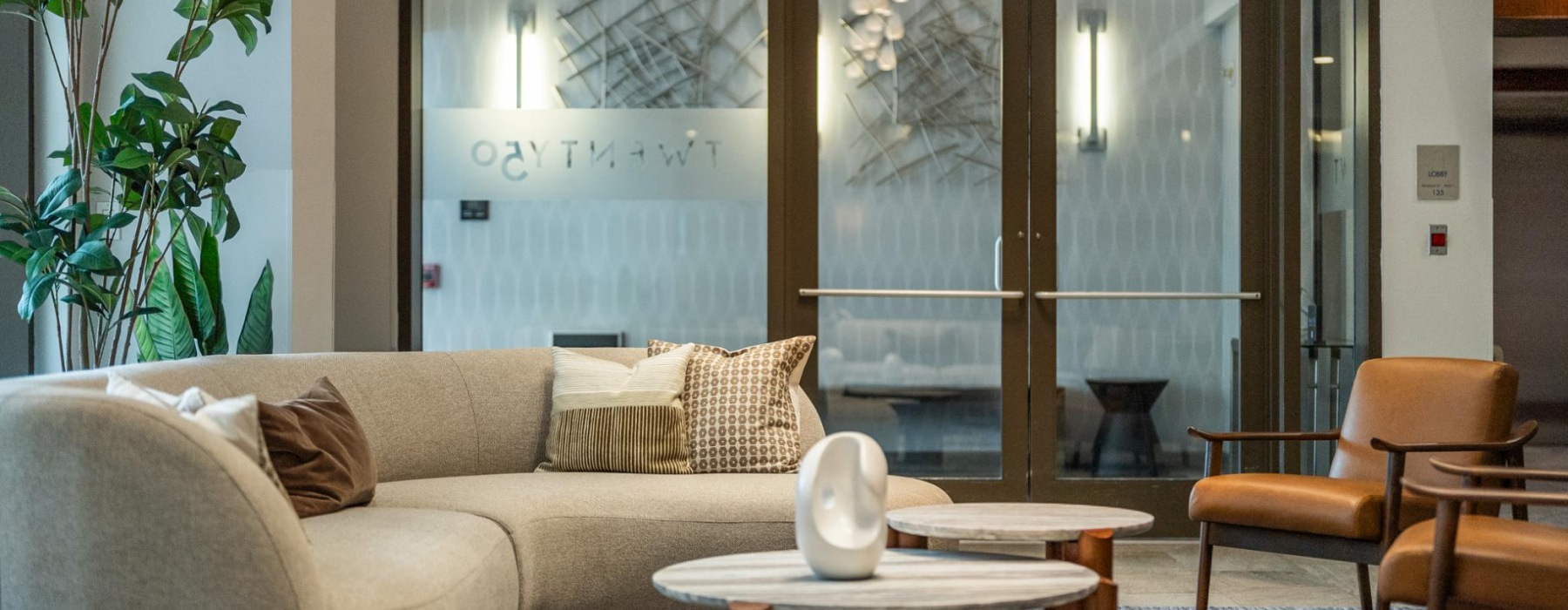 A closeup lobby lounge area showing sofa, 2 brown chairs, and a coffee table